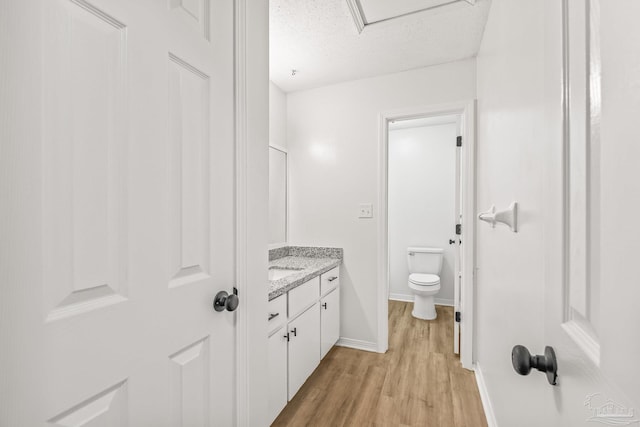 bathroom featuring vanity, toilet, wood-type flooring, and a textured ceiling