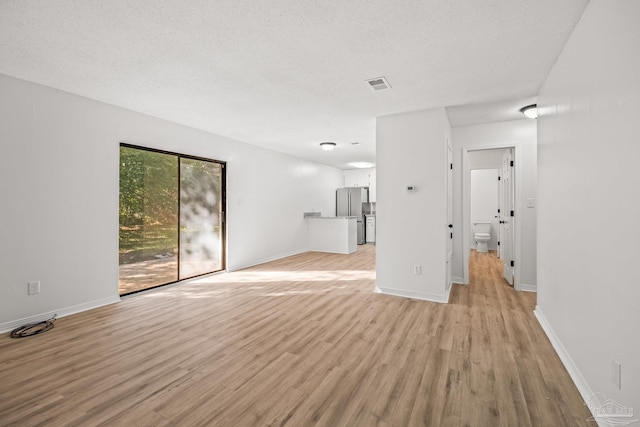 unfurnished living room featuring a textured ceiling and light hardwood / wood-style flooring