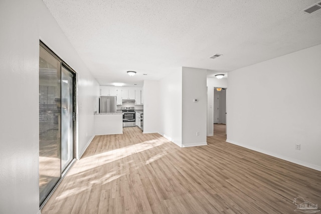 unfurnished living room with light wood-type flooring and a textured ceiling