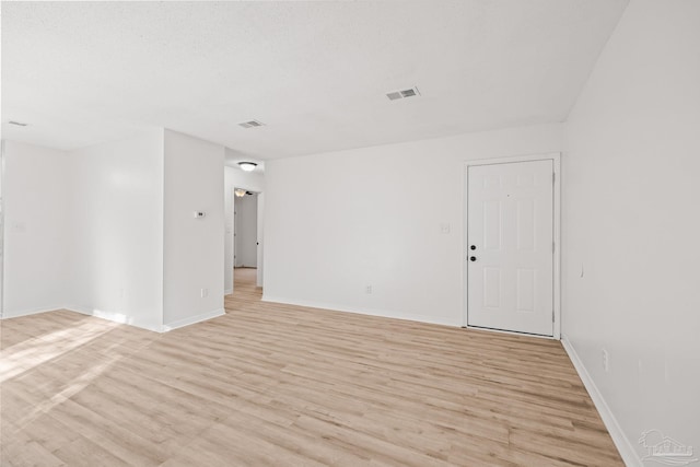 unfurnished room featuring light wood-type flooring and a textured ceiling