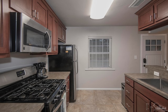 kitchen with light tile patterned floors, stainless steel appliances, and sink