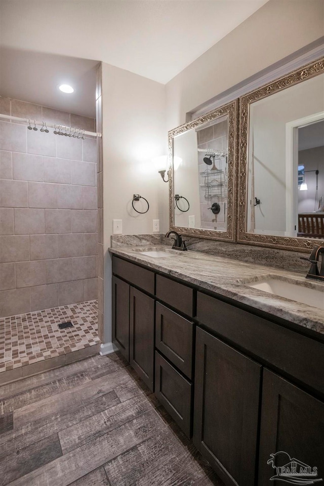 bathroom with tiled shower, vanity, and hardwood / wood-style flooring