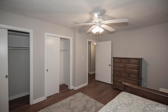 bedroom featuring ceiling fan, dark hardwood / wood-style floors, and two closets