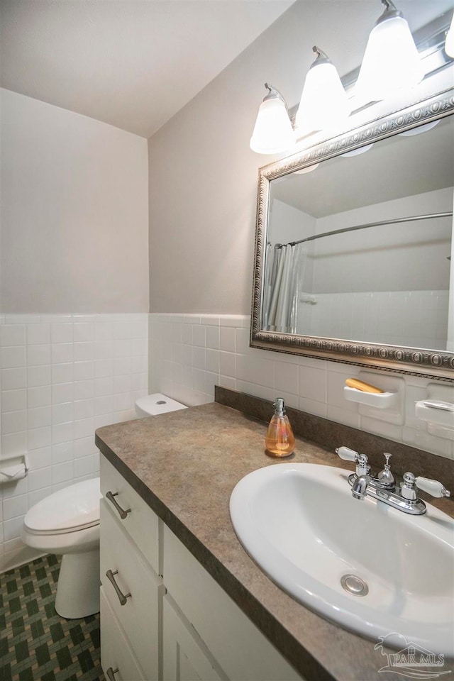 bathroom featuring vanity, a shower with curtain, tile patterned flooring, toilet, and tile walls