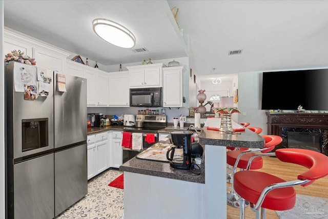 6819 Old W Ln, Milton, FL 32570 - kitchen featuring appliances with stainless steel finishes, dark countertops, white cabinets, a peninsula, and a kitchen bar