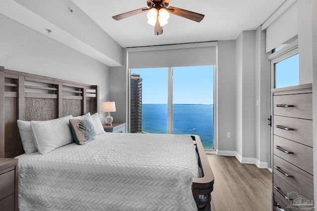 bedroom featuring access to exterior, ceiling fan, a water view, and light hardwood / wood-style floors