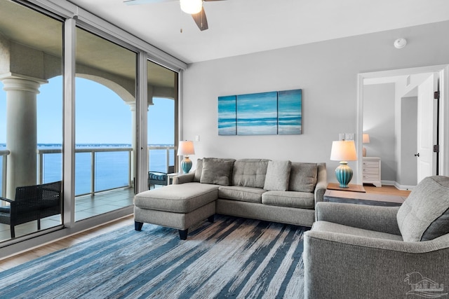 living room featuring a water view, ceiling fan, a wealth of natural light, and hardwood / wood-style flooring