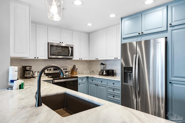 kitchen with light stone countertops, backsplash, hanging light fixtures, stainless steel appliances, and white cabinetry