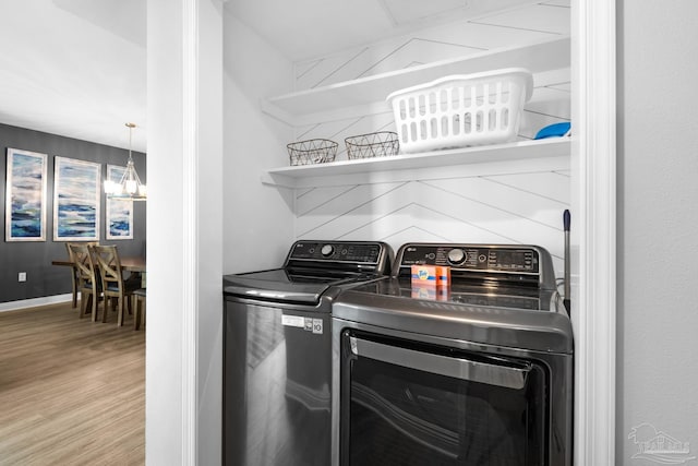 laundry area featuring light wood-type flooring, a chandelier, and washing machine and dryer