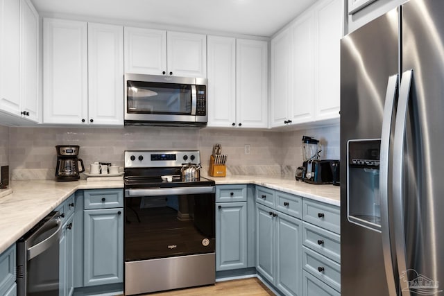 kitchen with stainless steel appliances, gray cabinets, white cabinetry, and tasteful backsplash