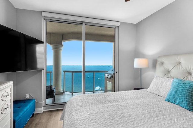 bedroom featuring a water view, hardwood / wood-style floors, and access to exterior