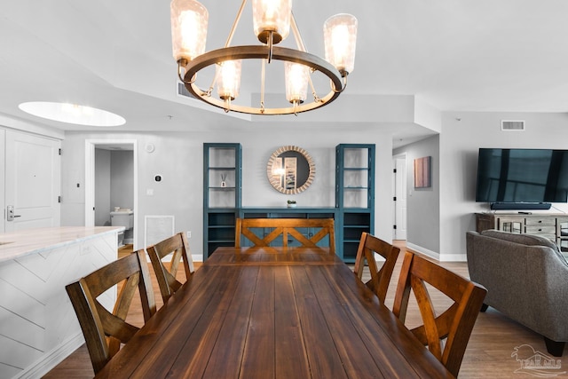 dining space featuring wood-type flooring and a notable chandelier