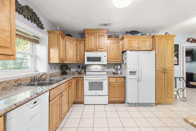 kitchen with sink, white appliances, a textured ceiling, light tile patterned floors, and light stone counters