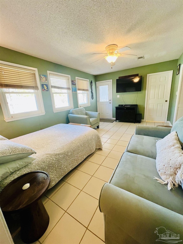 bedroom with ceiling fan, a textured ceiling, and light tile patterned floors