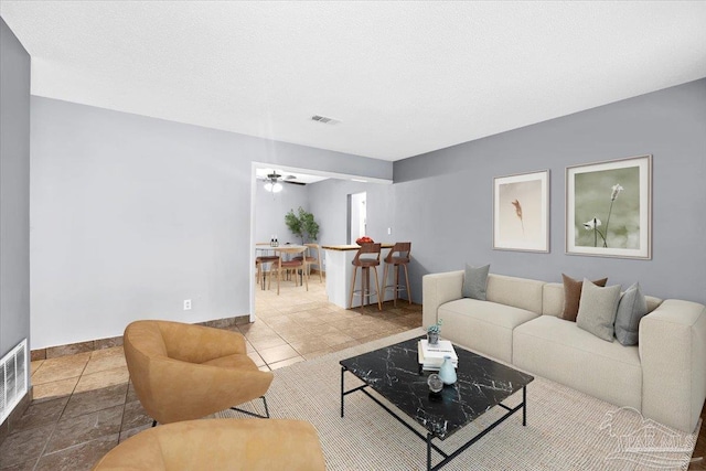 living room featuring a textured ceiling, tile patterned floors, and ceiling fan