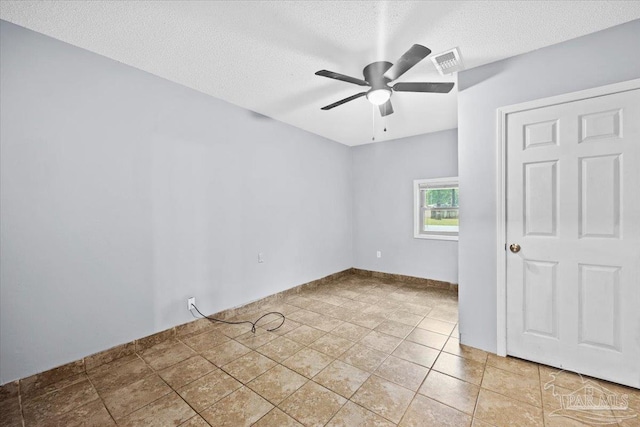 tiled spare room with ceiling fan and a textured ceiling