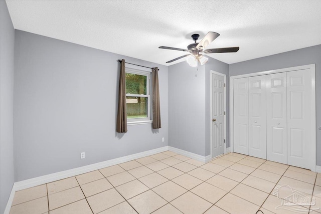 unfurnished bedroom featuring ceiling fan, a closet, light tile patterned flooring, and a textured ceiling