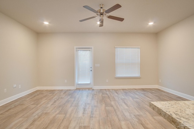 empty room with ceiling fan and light hardwood / wood-style floors