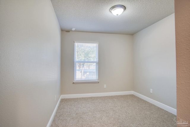 carpeted empty room featuring a textured ceiling