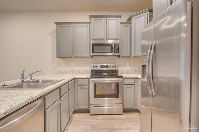 kitchen featuring sink, gray cabinets, light hardwood / wood-style floors, and appliances with stainless steel finishes