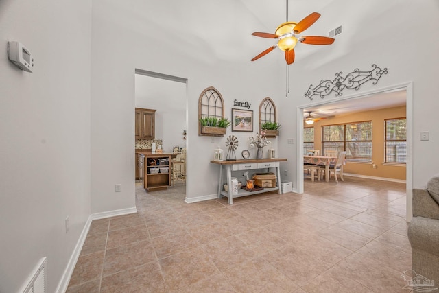 interior space with light tile patterned floors, a high ceiling, visible vents, and baseboards