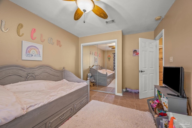 tiled bedroom with a closet, visible vents, and ceiling fan