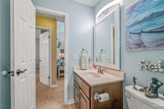 bathroom with toilet, tile patterned flooring, baseboards, and vanity