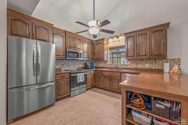 kitchen with backsplash, appliances with stainless steel finishes, vaulted ceiling, a sink, and ceiling fan