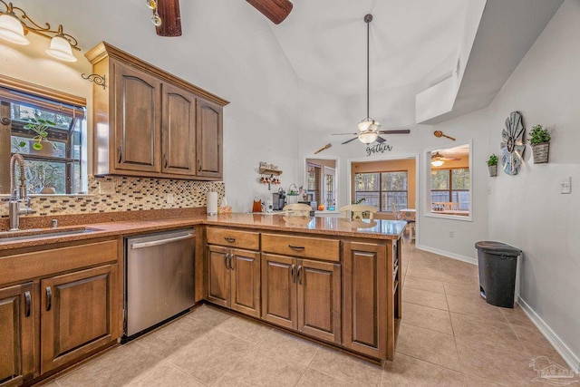 kitchen with light tile patterned floors, decorative backsplash, a sink, dishwasher, and a peninsula