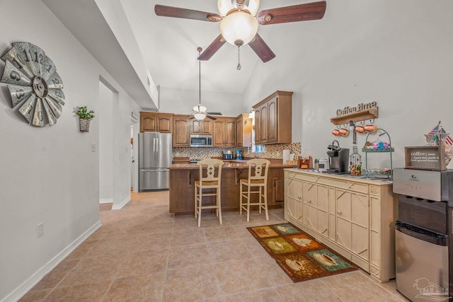 kitchen featuring decorative backsplash, appliances with stainless steel finishes, a breakfast bar, a peninsula, and vaulted ceiling