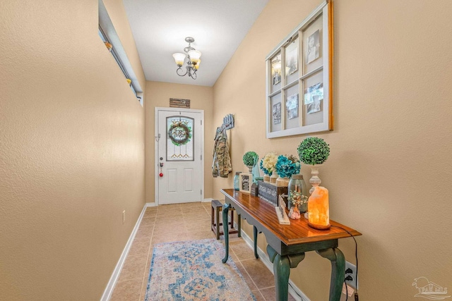 doorway to outside featuring a notable chandelier, baseboards, and tile patterned floors