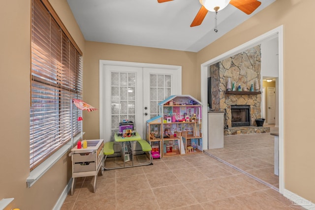 recreation room with french doors, a fireplace, tile patterned flooring, and a ceiling fan