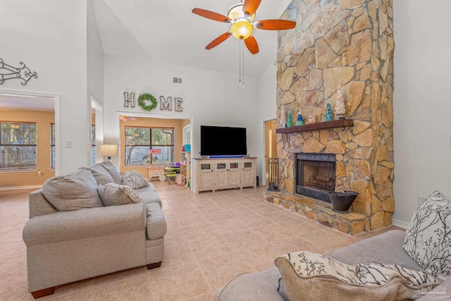 tiled living area with a fireplace, visible vents, ceiling fan, high vaulted ceiling, and baseboards