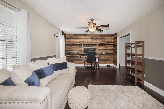 living room with ceiling fan, wooden walls, a textured ceiling, and hardwood / wood-style floors