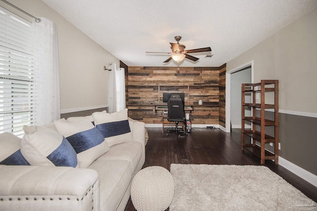 living room featuring dark hardwood / wood-style flooring, ceiling fan, a textured ceiling, and wood walls