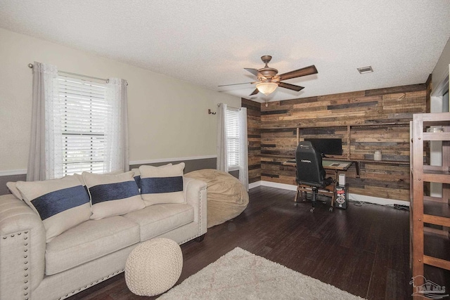 living room featuring dark hardwood / wood-style flooring, plenty of natural light, a textured ceiling, and wooden walls