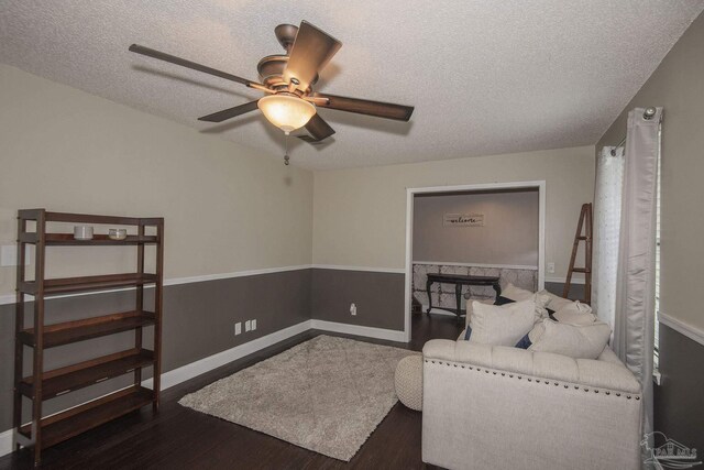 living room with ceiling fan, hardwood / wood-style flooring, a textured ceiling, and a brick fireplace