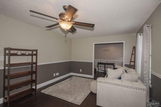 living area with dark hardwood / wood-style flooring, ceiling fan, and a textured ceiling