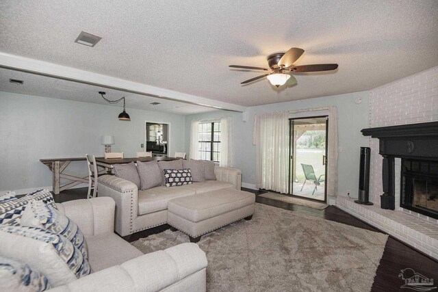 living room featuring a textured ceiling, ceiling fan, dark hardwood / wood-style flooring, and a brick fireplace