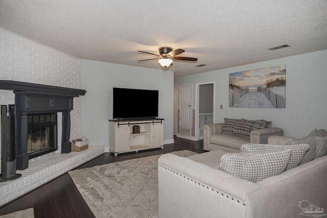 living room featuring dark hardwood / wood-style flooring, a textured ceiling, a fireplace, and ceiling fan