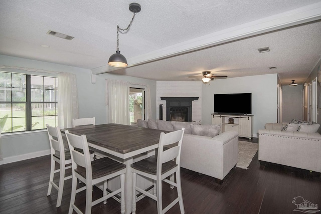 dining area featuring dark wood-type flooring, ceiling fan, plenty of natural light, and a fireplace