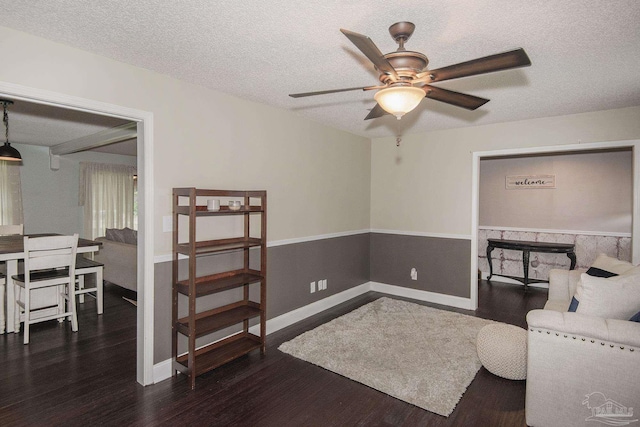 living area featuring ceiling fan, dark hardwood / wood-style floors, and a textured ceiling