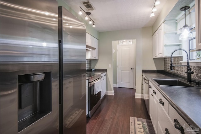 kitchen featuring appliances with stainless steel finishes, sink, white cabinets, dark hardwood / wood-style flooring, and hanging light fixtures