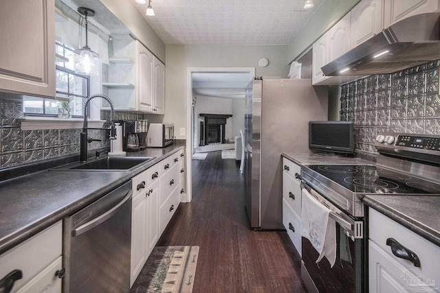 kitchen with appliances with stainless steel finishes, tasteful backsplash, sink, white cabinets, and hanging light fixtures