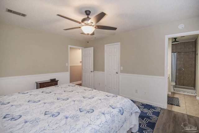 bedroom with tile patterned floors, ceiling fan, ensuite bathroom, and a textured ceiling