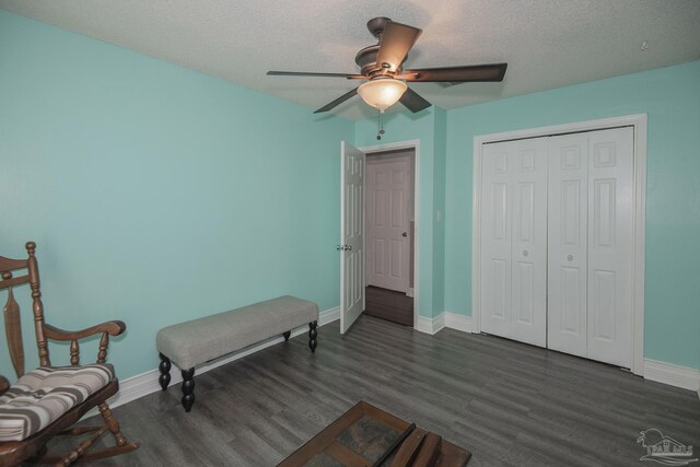 unfurnished bedroom featuring ceiling fan, a closet, dark wood-type flooring, and a textured ceiling