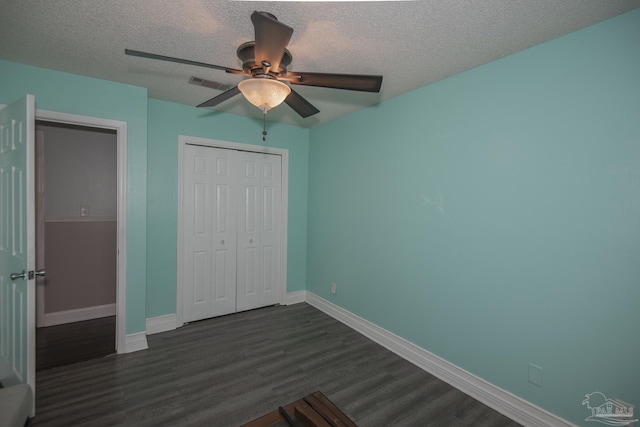 unfurnished bedroom featuring ceiling fan, dark wood-type flooring, a textured ceiling, and a closet