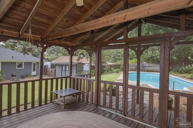 wooden terrace featuring a storage unit, a yard, and a fenced in pool