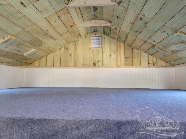 additional living space with wood walls, wooden ceiling, lofted ceiling, and carpet