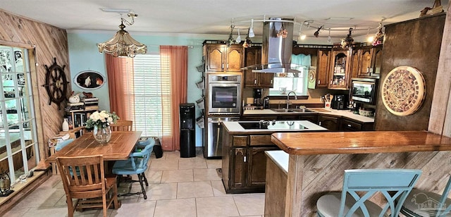 kitchen with a sink, island exhaust hood, stainless steel microwave, a kitchen island, and black electric cooktop